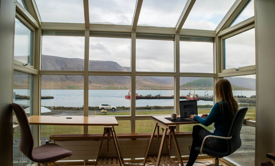 Remote Employee Working by the Window | How to Manage Remote Teams Using Global HR Specialists - TopSource Blog