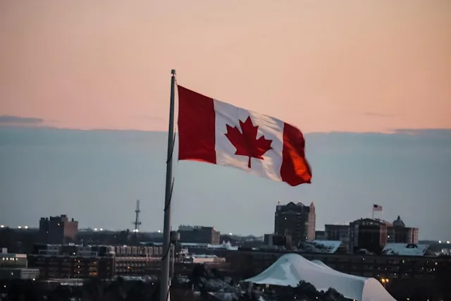 Canadian flag at sunset over a city skyline, Canada