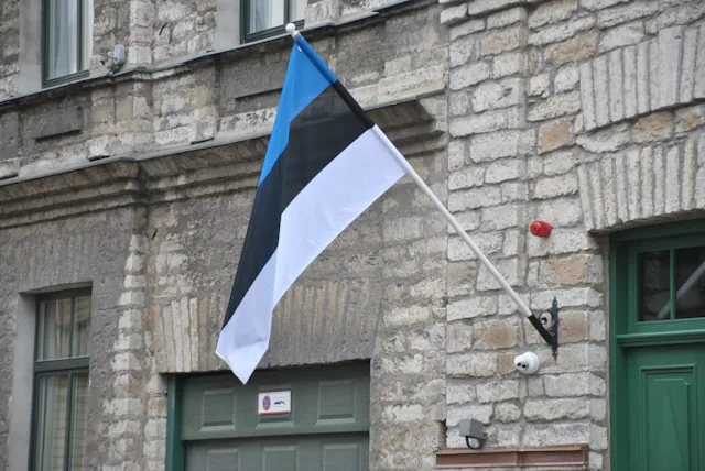 The Estonian national flag (blue, black and white) on a stone building in Tallinn
