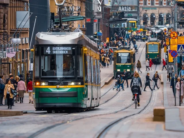 A green tram on a busy street in central Helsinki, Finland