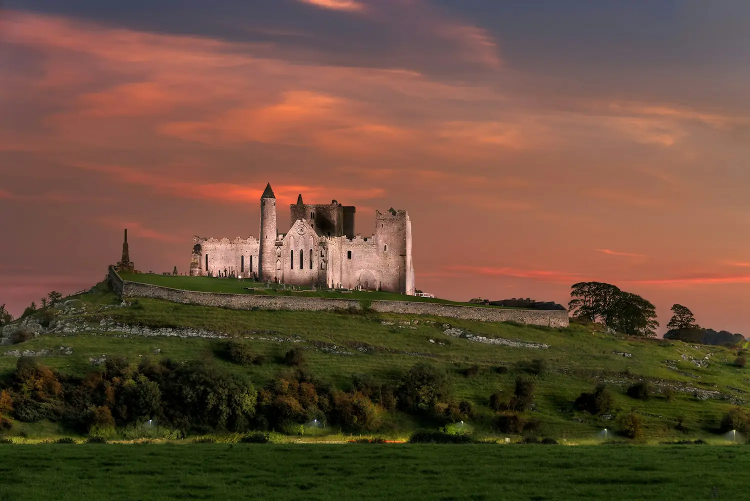 The Rock of Cashel floodlit against a sunset sky in County Tipperary, Ireland