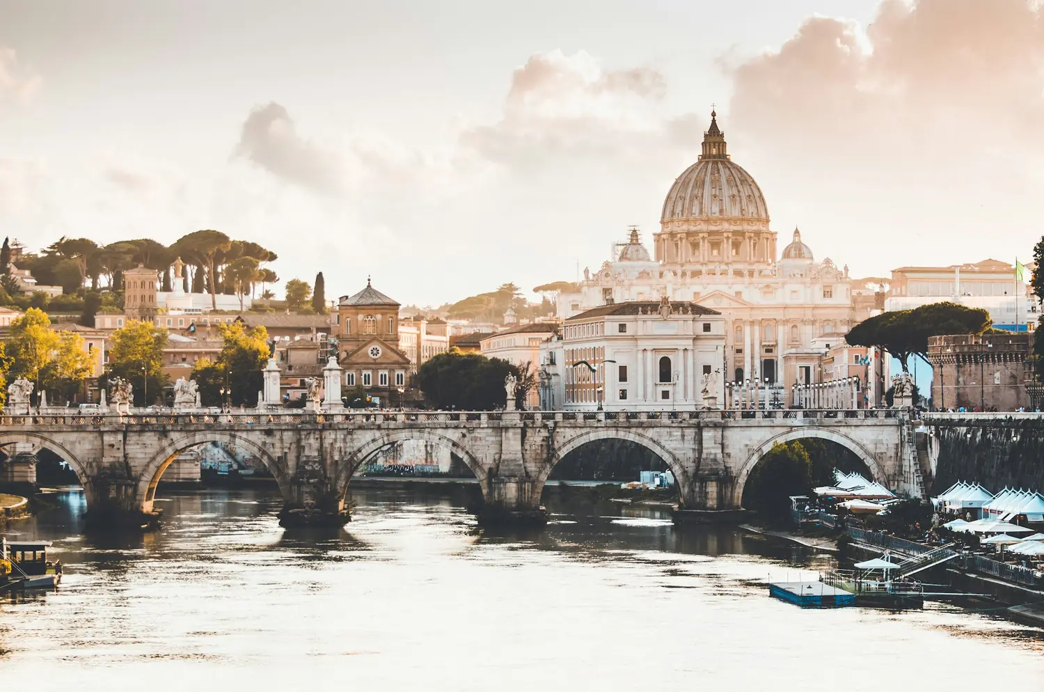 St. Peter's Basilica and a bridge over the Tiber at golden hour in Rome, Italy