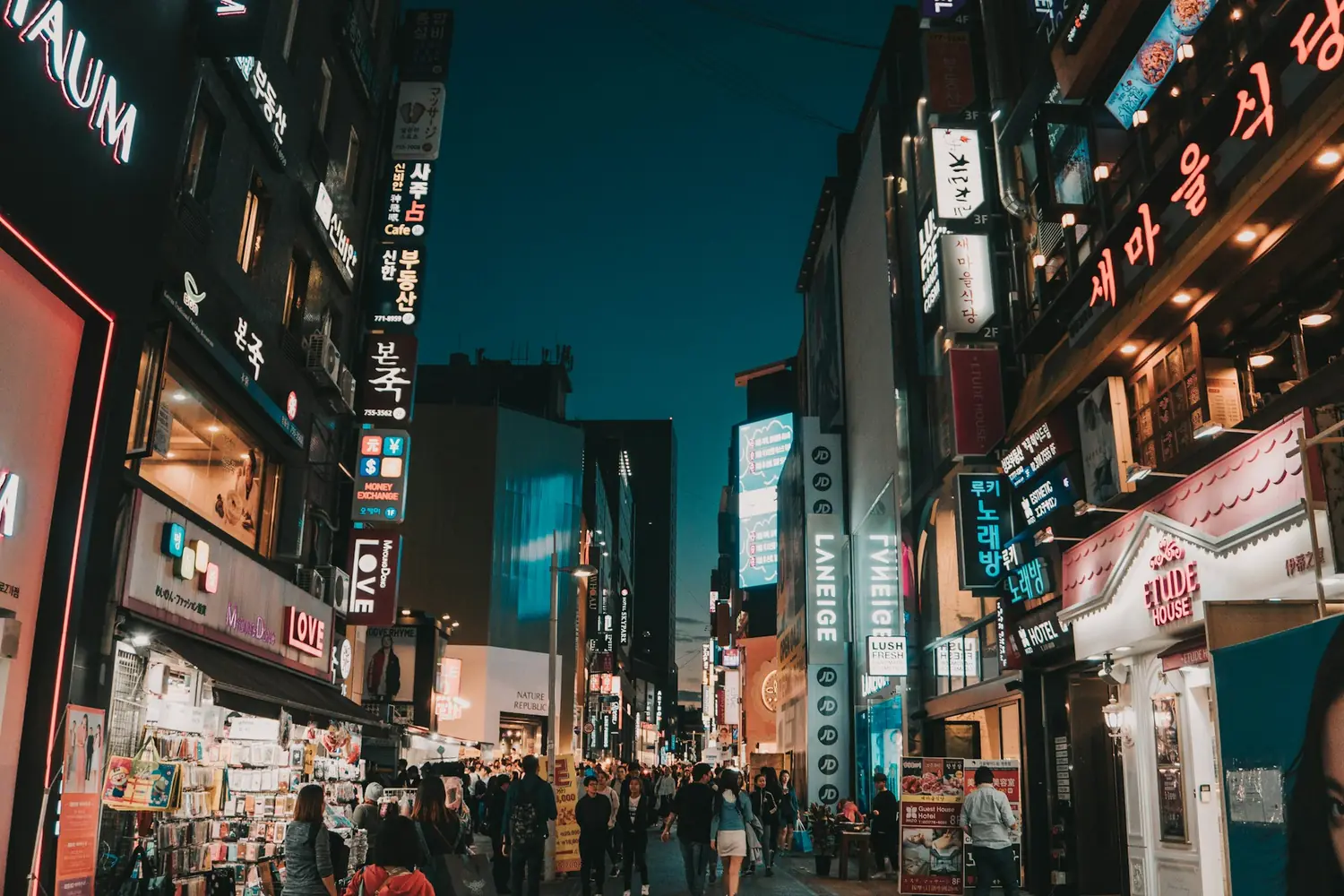 Crowds and illuminated Korean shop signs along a Myeongdong shopping street at dusk, Seoul, South Korea