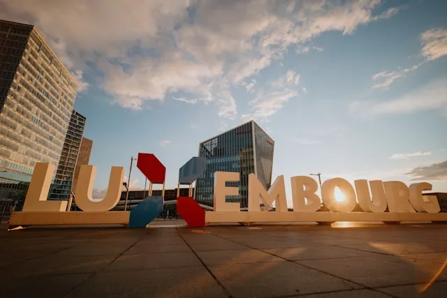 The LUXEMBOURG letters sculpture with office towers at sunset in Kirchberg, Luxembourg