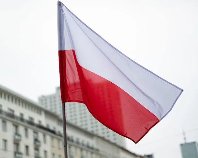 The Polish flag flying above city buildings against a pale sky, Poland
