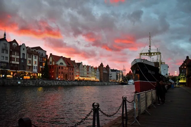 The Motlawa riverfront in Gdansk at sunset, with the old town townhouses and a moored ship, Poland