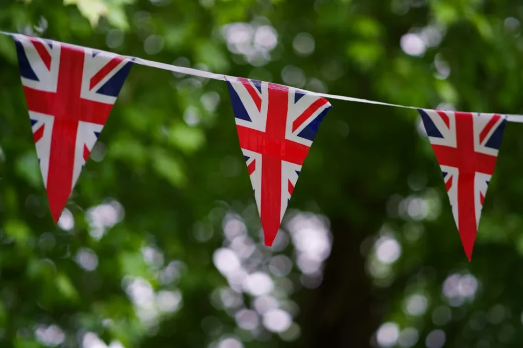 A string of Union Jack bunting hanging against green summer foliage, United Kingdom
