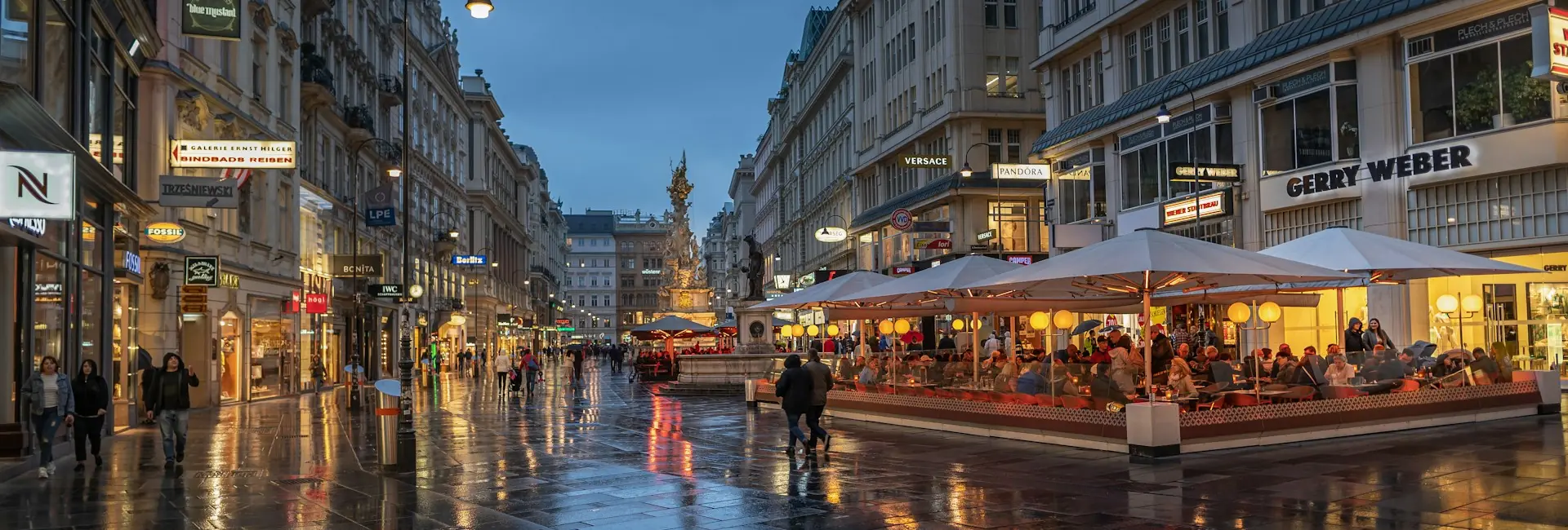 The Graben in central Vienna at dusk, with shops, cafe terraces and the Plague Column, Austria
