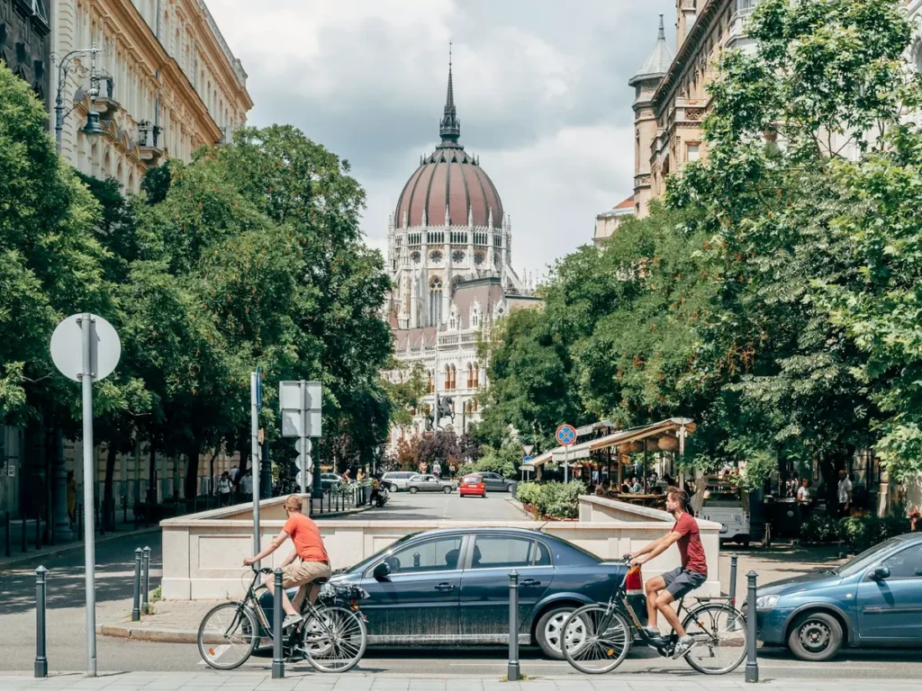 Cyclists on a street in central Budapest with the dome of the Parliament behind, Budapest, Hungary