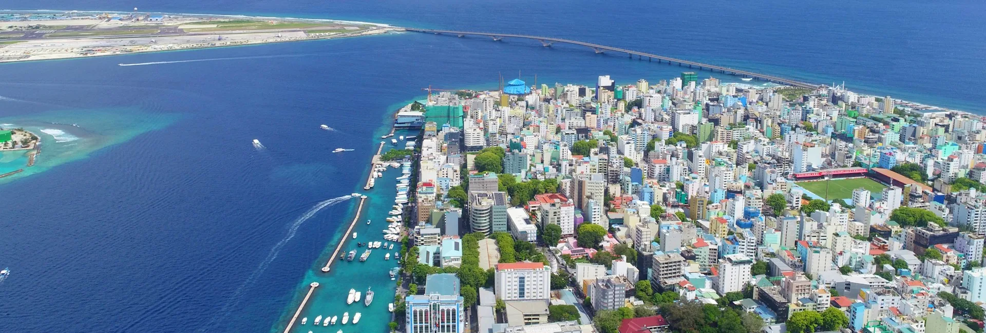 Aerial view of Male with its harbour in the foreground and the Sinamale Bridge crossing to Hulhule and Velana International Airport, Maldives