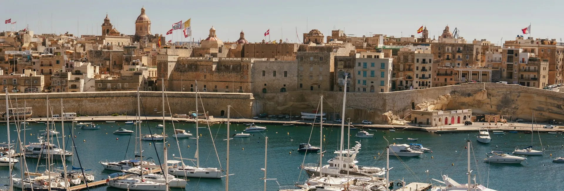 Birgu seen across Dockyard Creek in the Grand Harbour, with the stone fortifications, the dome of St Lawrence and the marina in front, Malta