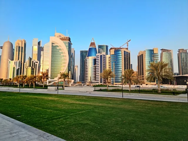 West Bay office towers seen across the lawns and palm trees of Al Bidda Park, Doha, Qatar
