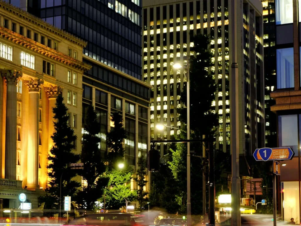 Office towers with lit windows above the Babasakimon crossing on Hibiya-dori in the Marunouchi business district at night, Tokyo, Japan