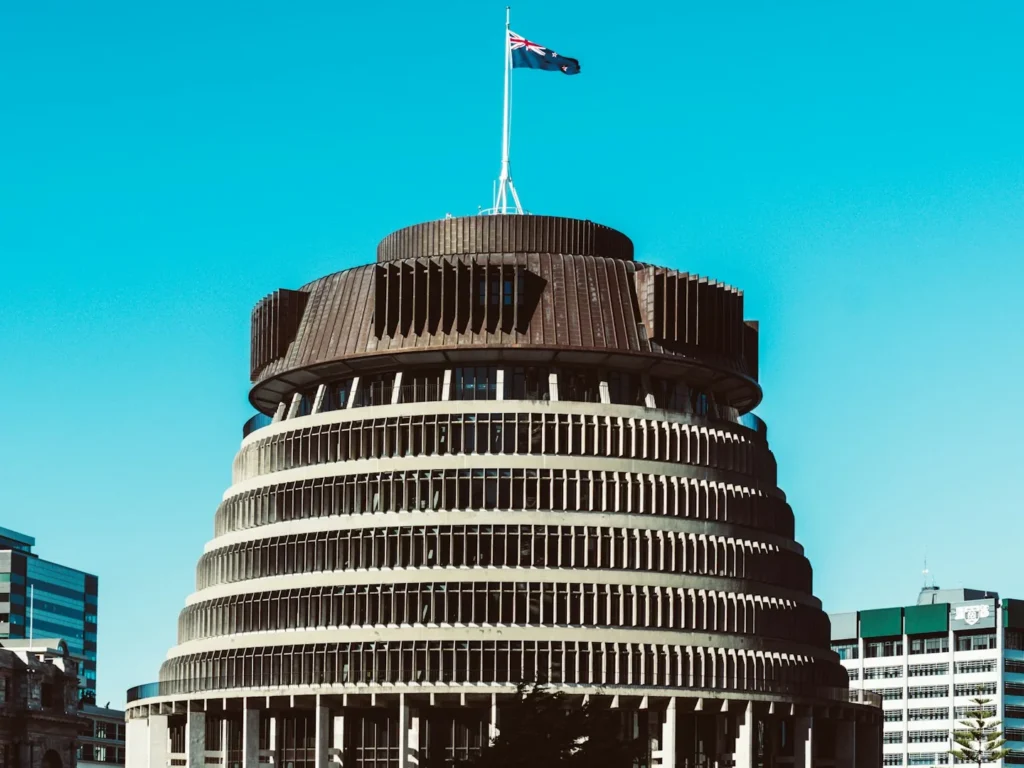 The Beehive in Wellington with the New Zealand flag flying on the roof, beside the Parliament buildings and a Victoria University office block, Wellington, New Zealand