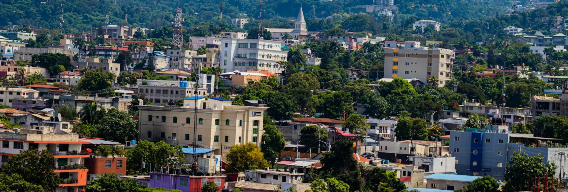 Buildings, trees and a church spire on the hillsides of Pétion-Ville, Haiti